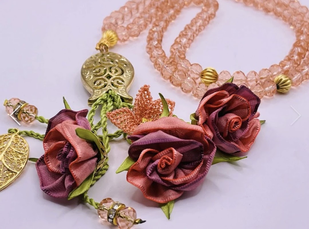 Close-up of elegant pink prayer beads with decorative fabric roses and gold-tone accents.