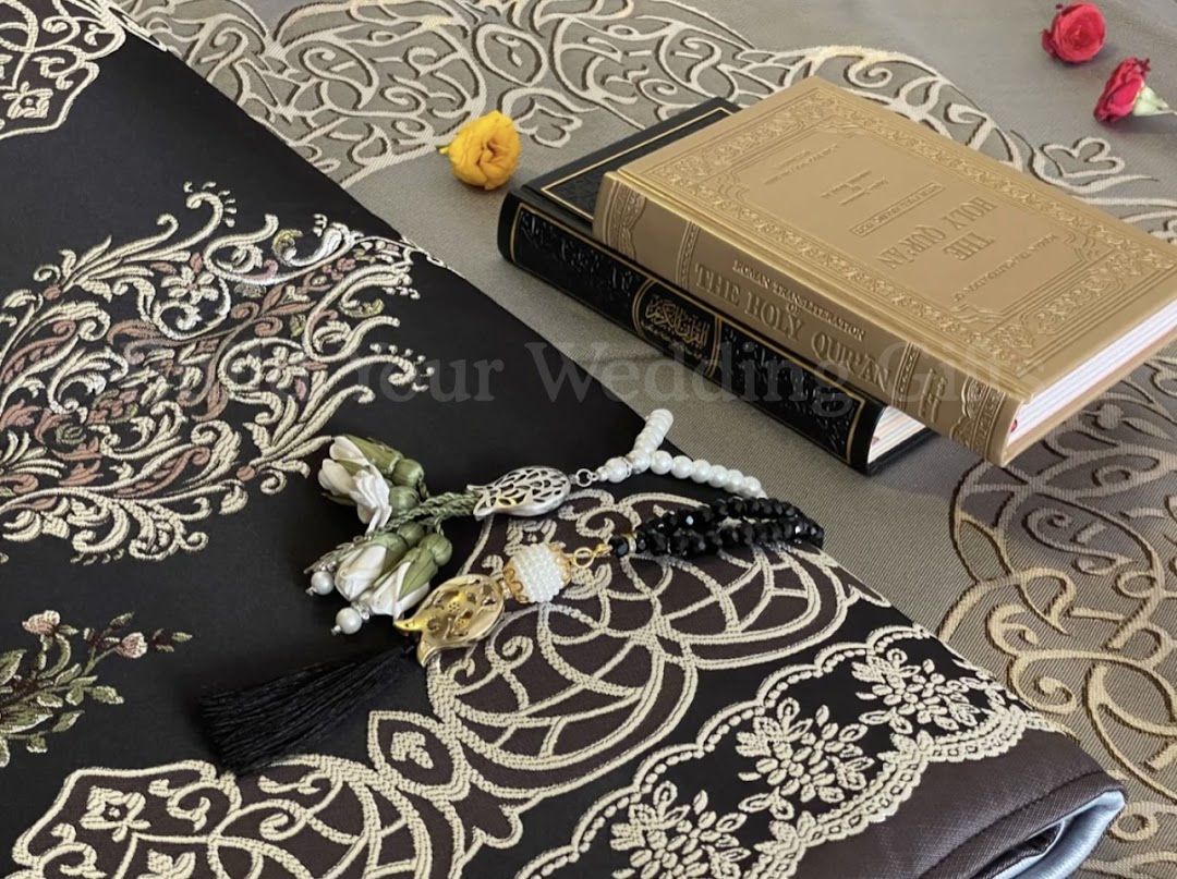 A close-up of Islamic gifts including Holy Qurans, prayer beads, and an intricately embroidered prayer mat.