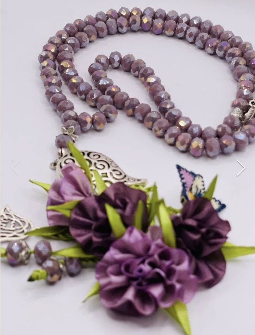 Close-up of elegant purple beaded prayer beads with floral and butterfly embellishments.