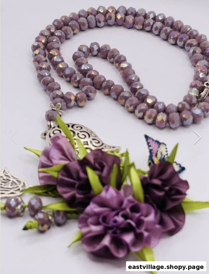 Close-up of elegant purple beaded prayer beads with floral and butterfly embellishments.