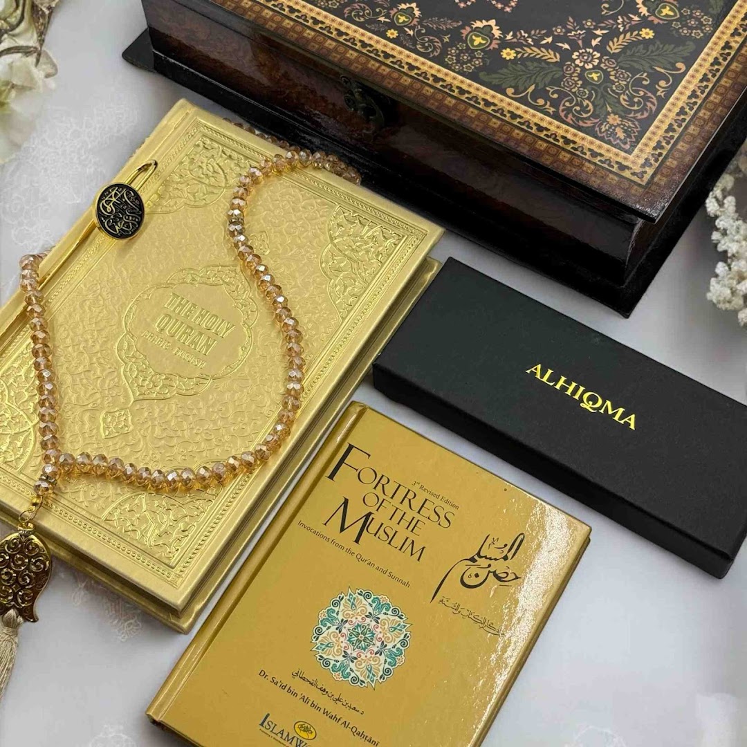 A collection of Islamic gifts including a golden Holy Quran, prayer beads, and an Islamic book.