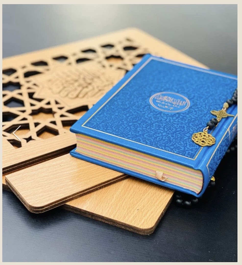 A blue Quran with prayer beads and a wooden stand featuring Islamic patterns.
