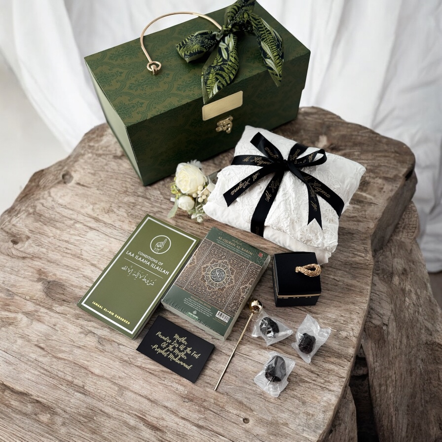 A curated collection of Islamic gifts, including a Quran, prayer mat, and dates, presented in a decorative box.