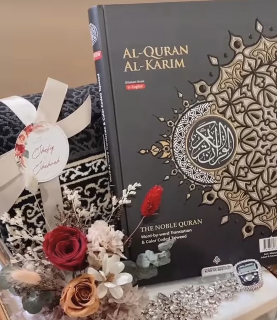 A beautifully arranged Islamic gift set featuring an Al-Quran, prayer mat, and decorative flowers.