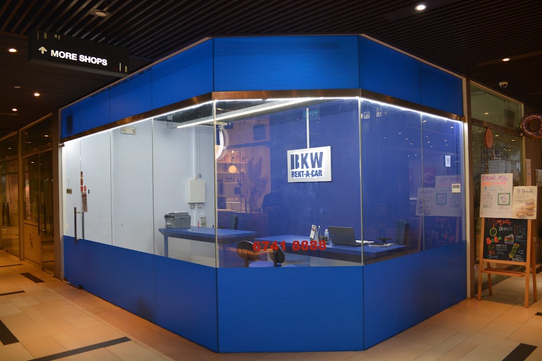 The exterior of BKW Rent A Car, a blue and white glass-fronted shop with a counter inside.