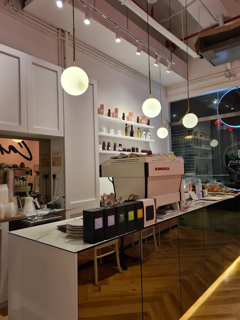 Interior view of Café Cartisan's counter with a coffee machine, T2 teas, and product shelves.
