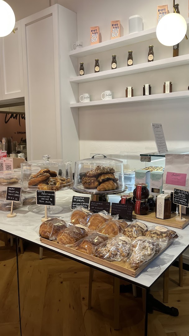 A vibrant display counter inside Café Cartisan, featuring freshly baked pastries, croissants, and retail coffee products.