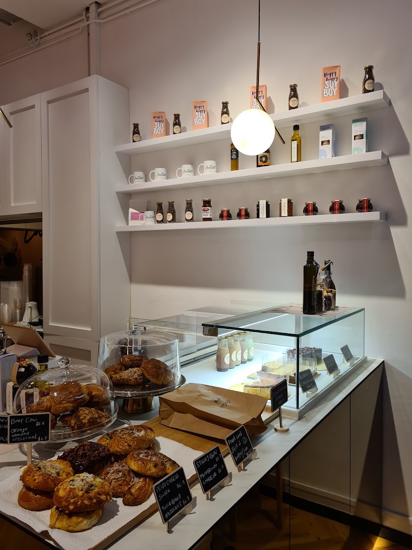 An inviting interior view of Café Cartisan, showcasing a counter filled with fresh pastries and shelves stocked with coffee products.
