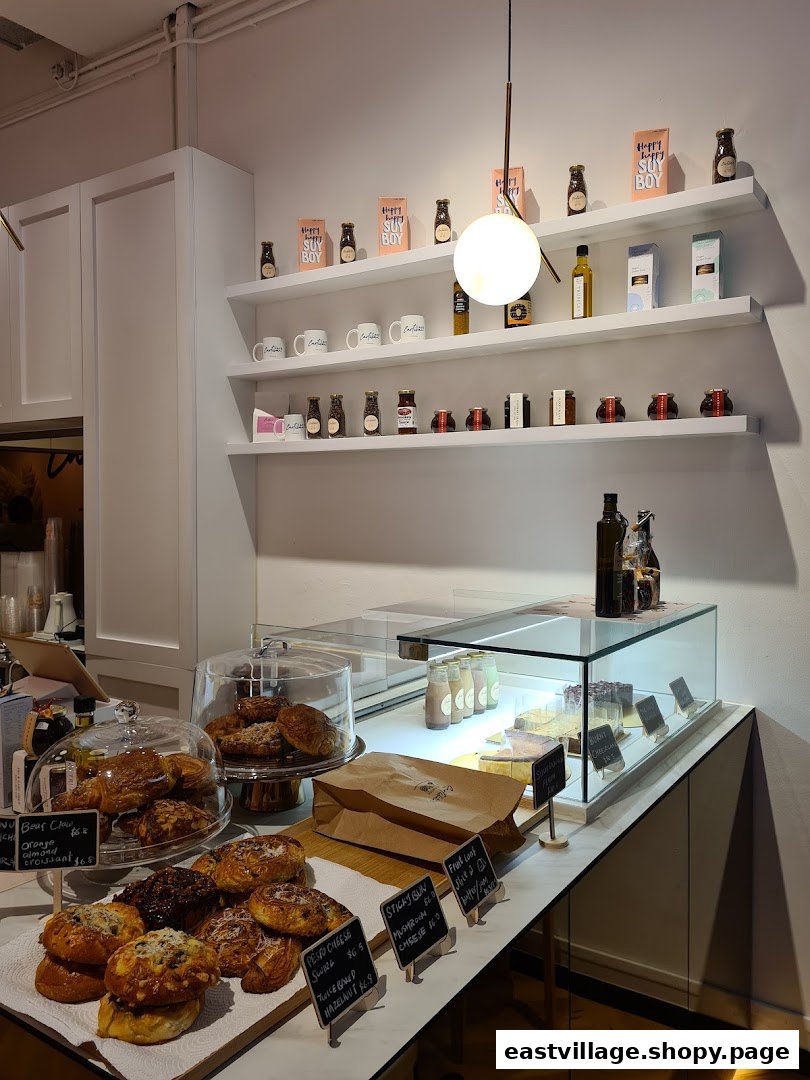 An inviting interior view of Café Cartisan, showcasing a counter filled with fresh pastries and shelves stocked with coffee products.