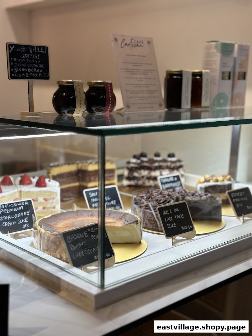 A display case showcasing a variety of delicious cakes and artisanal jams at Café Cartisan.