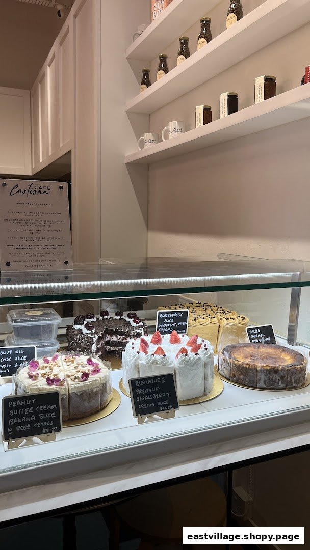 A display case filled with delicious cakes and pastries at Café Cartisan, with retail products on shelves.