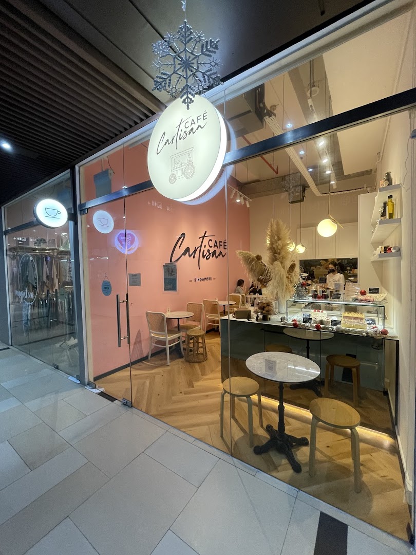 The inviting glass storefront of Café Cartisan Specialty Coffee, featuring a pink interior and display counter.