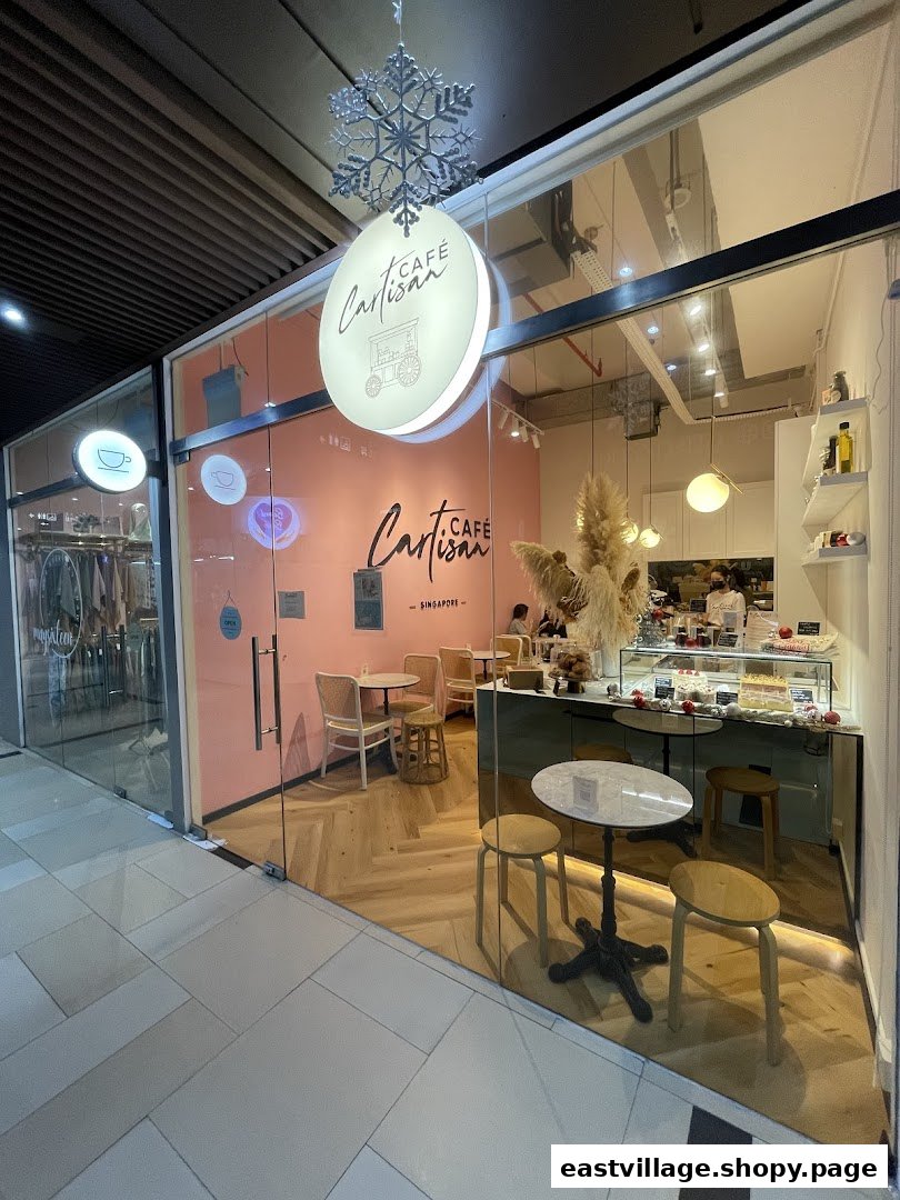The inviting glass storefront of Café Cartisan Specialty Coffee, featuring a pink interior and display counter.