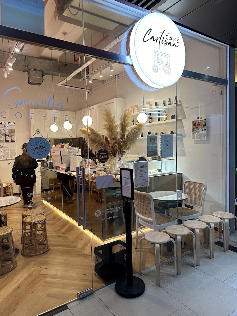 The inviting glass storefront of Café Cartisan Specialty Coffee, showcasing its modern interior and outdoor seating.