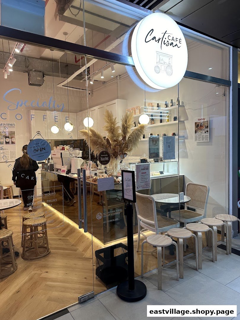 The inviting glass storefront of Café Cartisan Specialty Coffee, showcasing its modern interior and outdoor seating.