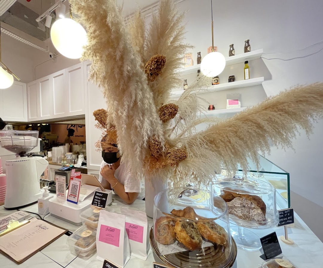 Interior view of Café Cartisan's counter, featuring pastries, coffee equipment, and a staff member.