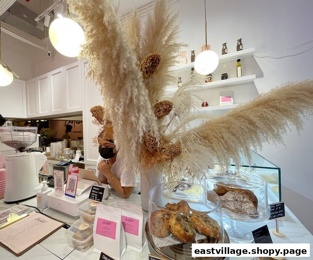 Interior view of Café Cartisan's counter, featuring pastries, coffee equipment, and a staff member.