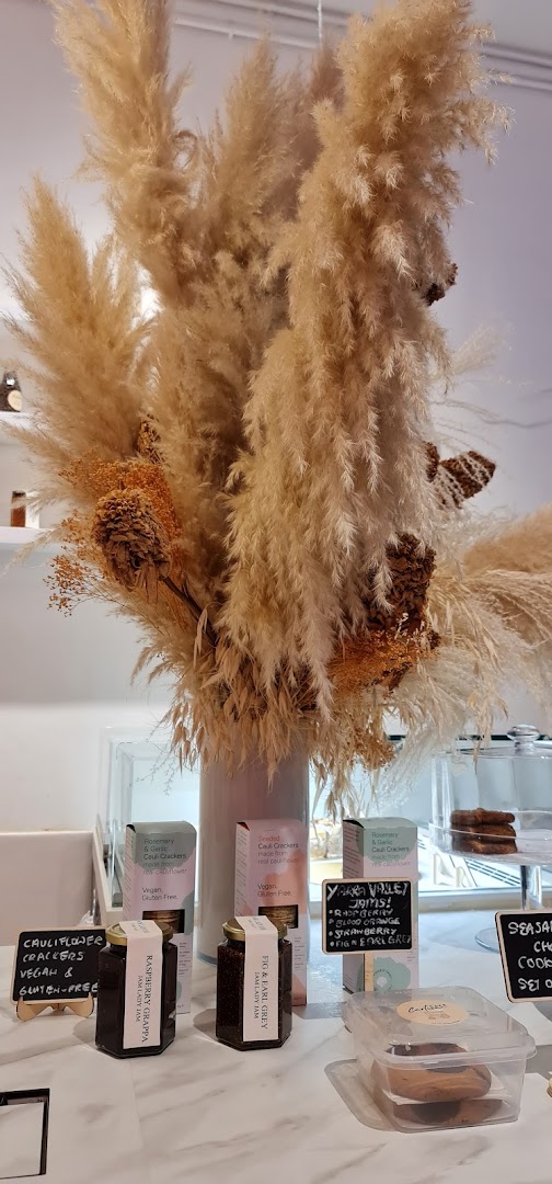 An inviting display of artisanal jams, gourmet crackers, and cookies, adorned with decorative pampas grass.