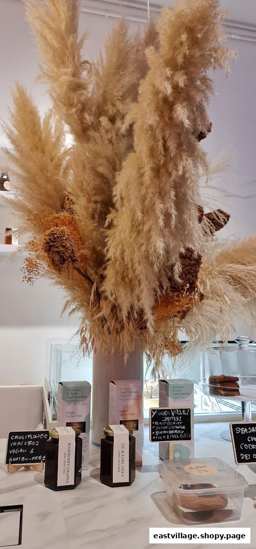 An inviting display of artisanal jams, gourmet crackers, and cookies, adorned with decorative pampas grass.