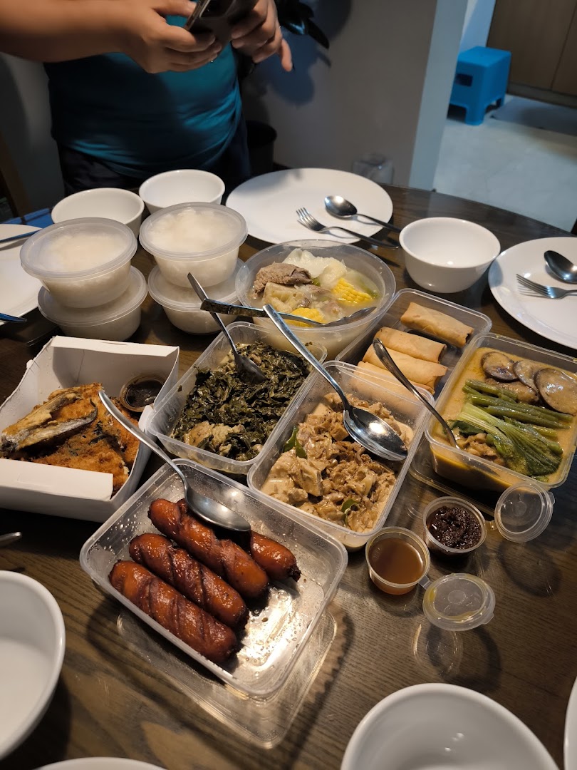 A table filled with various Filipino dishes in takeout containers, including rice, soup, and fried items.