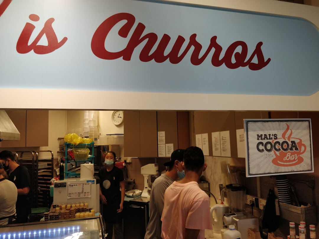 Interior view of Chulop! by The Syarifs, showing the counter, staff, customers, and 'is Churros' sign.