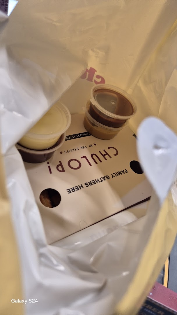 Inside a Chulop! by The Syarifs takeaway bag with food containers and branding.