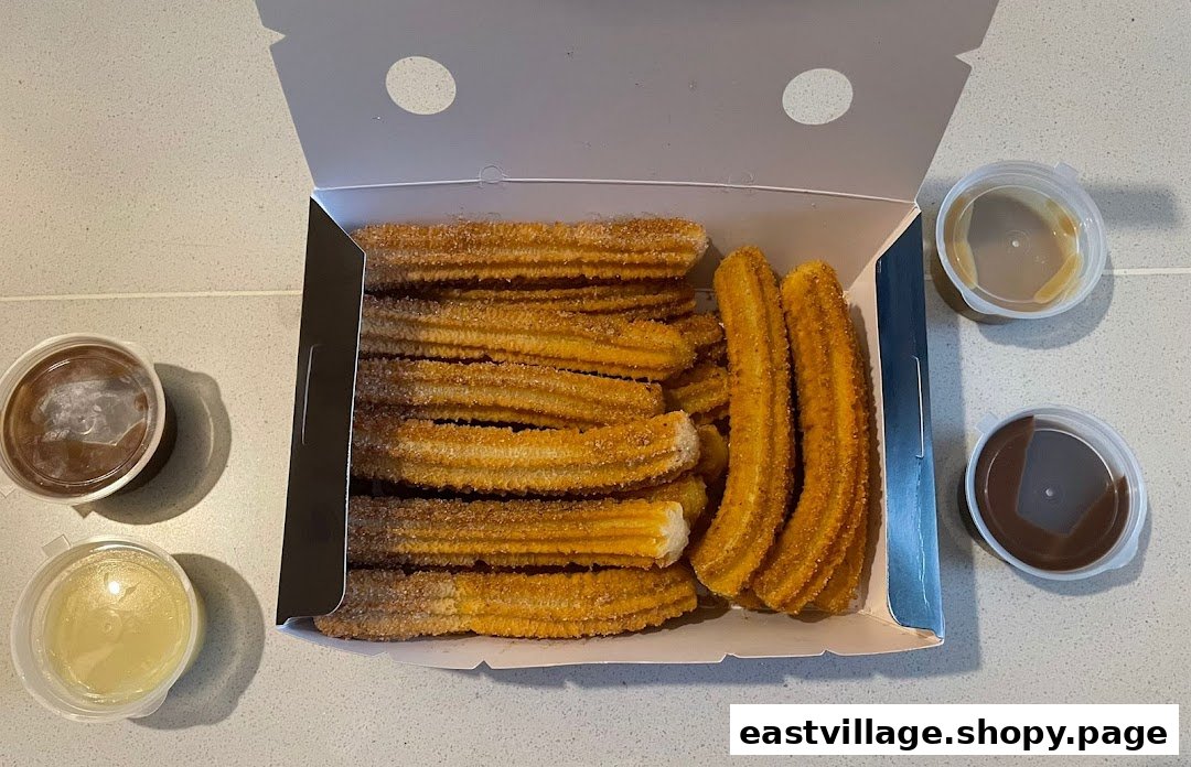 A box of golden churros with three dipping sauces, ready to enjoy.