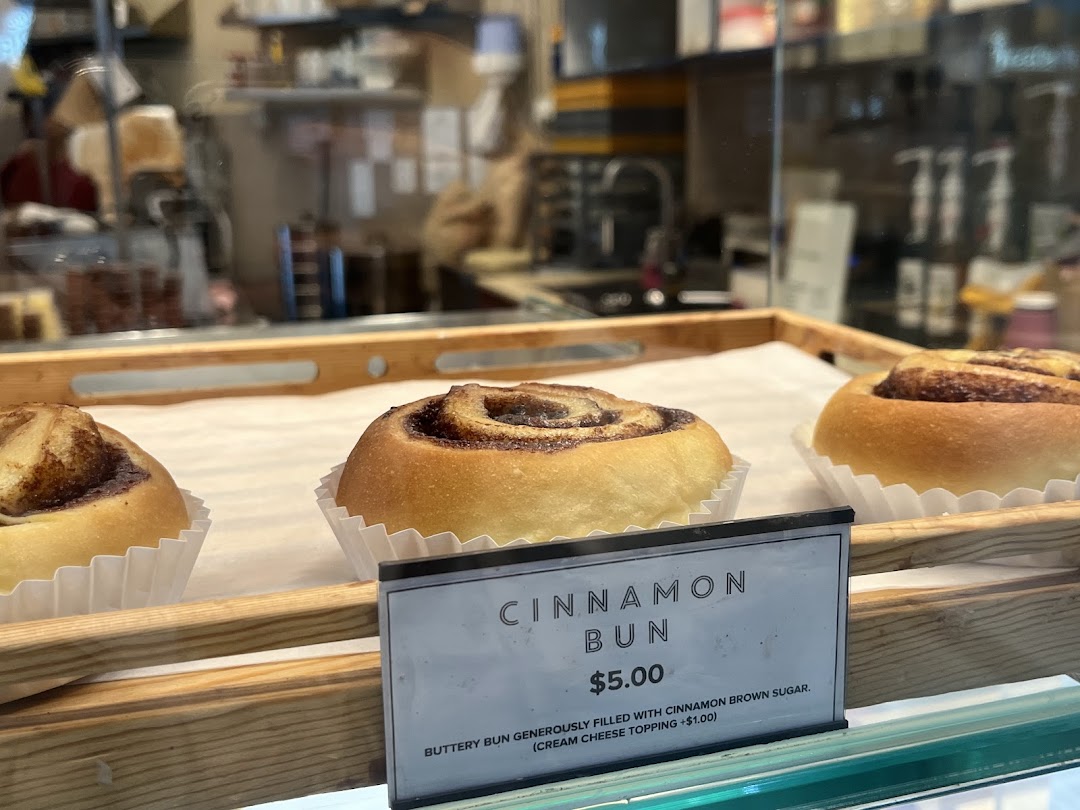 Delicious cinnamon buns displayed in a bakery, with a clear price and description tag.