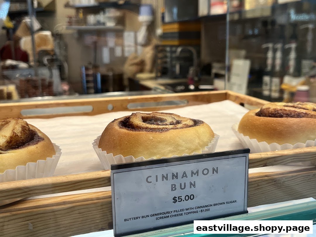 Delicious cinnamon buns displayed in a bakery, with a clear price and description tag.