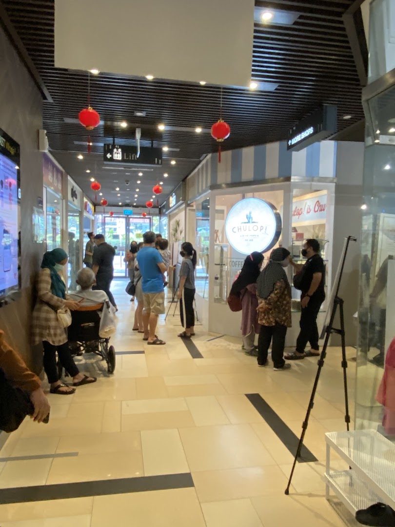Customers queue outside Chulop! by The Syarifs, a popular shop with a distinctive circular sign.