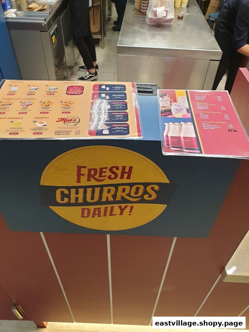A counter at Chulop! by The Syarifs displaying menus for fresh churros, hot cocoa, milkshakes, and other beverages.