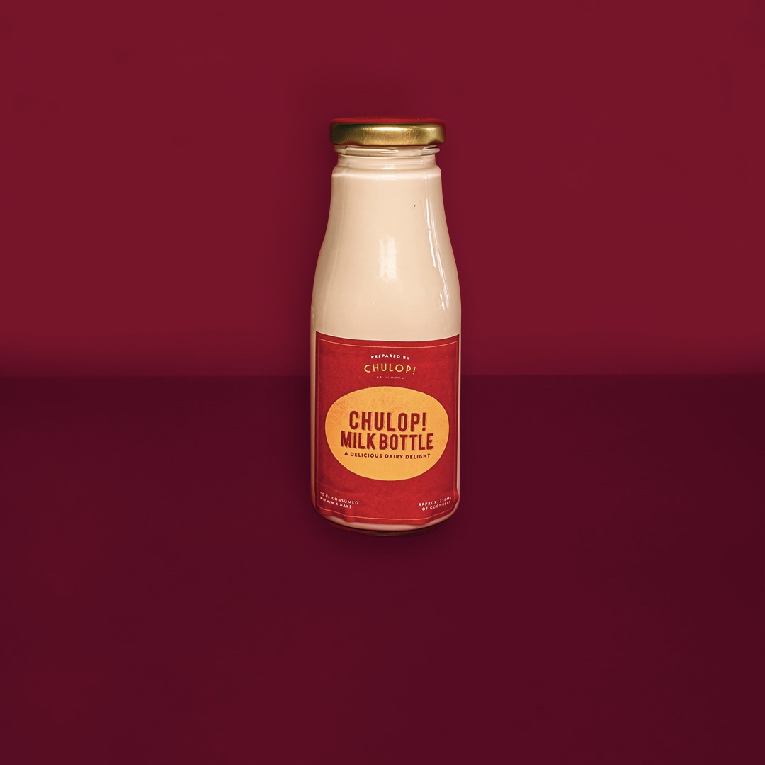 A Chulop! Milk Bottle, a delicious dairy delight, stands against a rich red background.