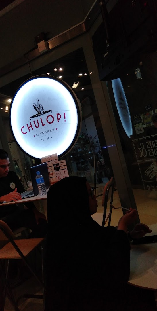 Interior view of Chulop! by The Syarifs, featuring its distinctive circular sign and customers.