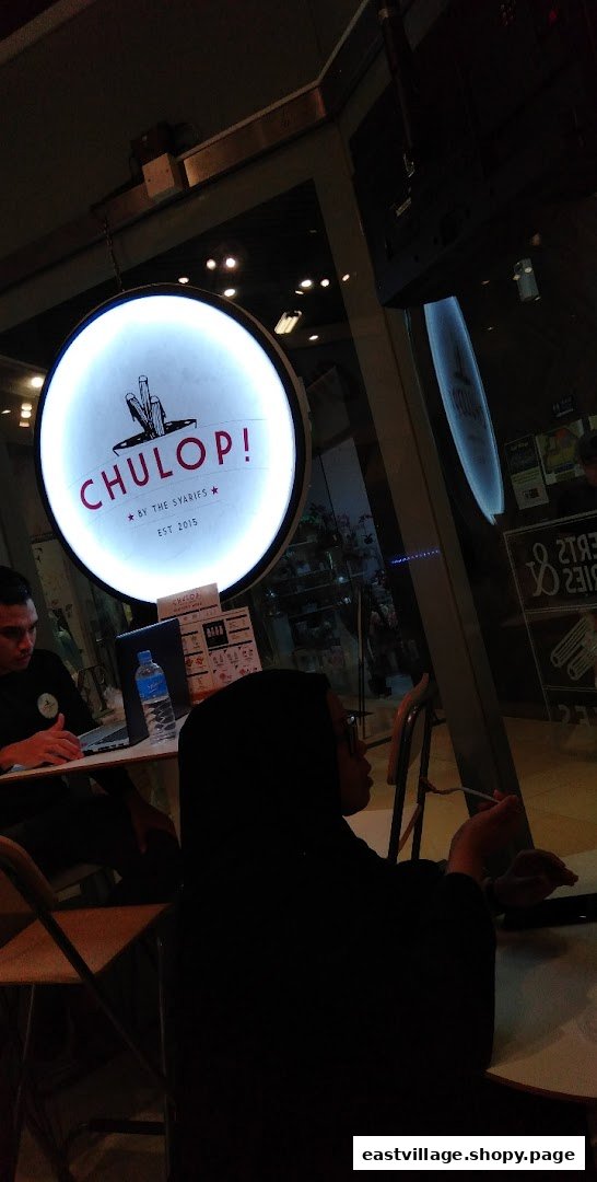 Interior view of Chulop! by The Syarifs, featuring its distinctive circular sign and customers.