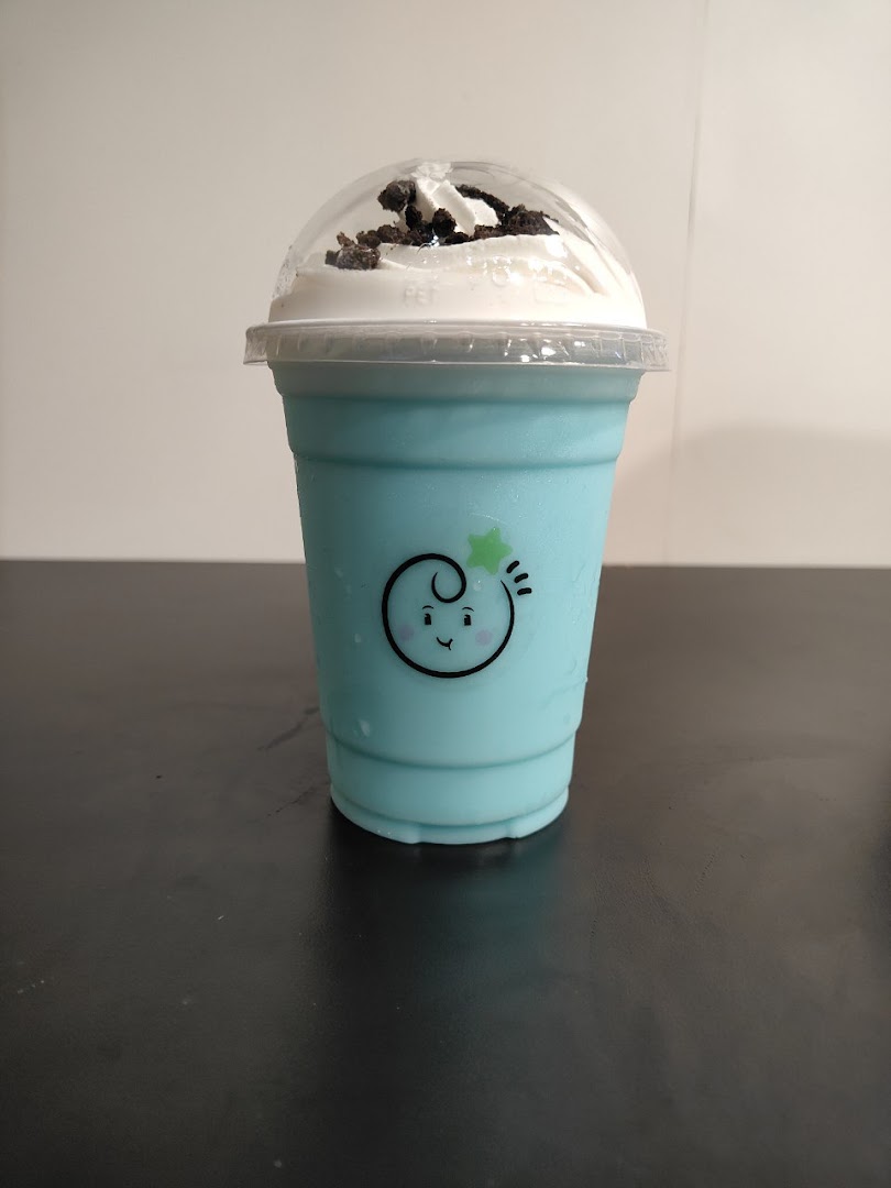 A vibrant blue drink topped with whipped cream and cookie crumbs in a clear cup.