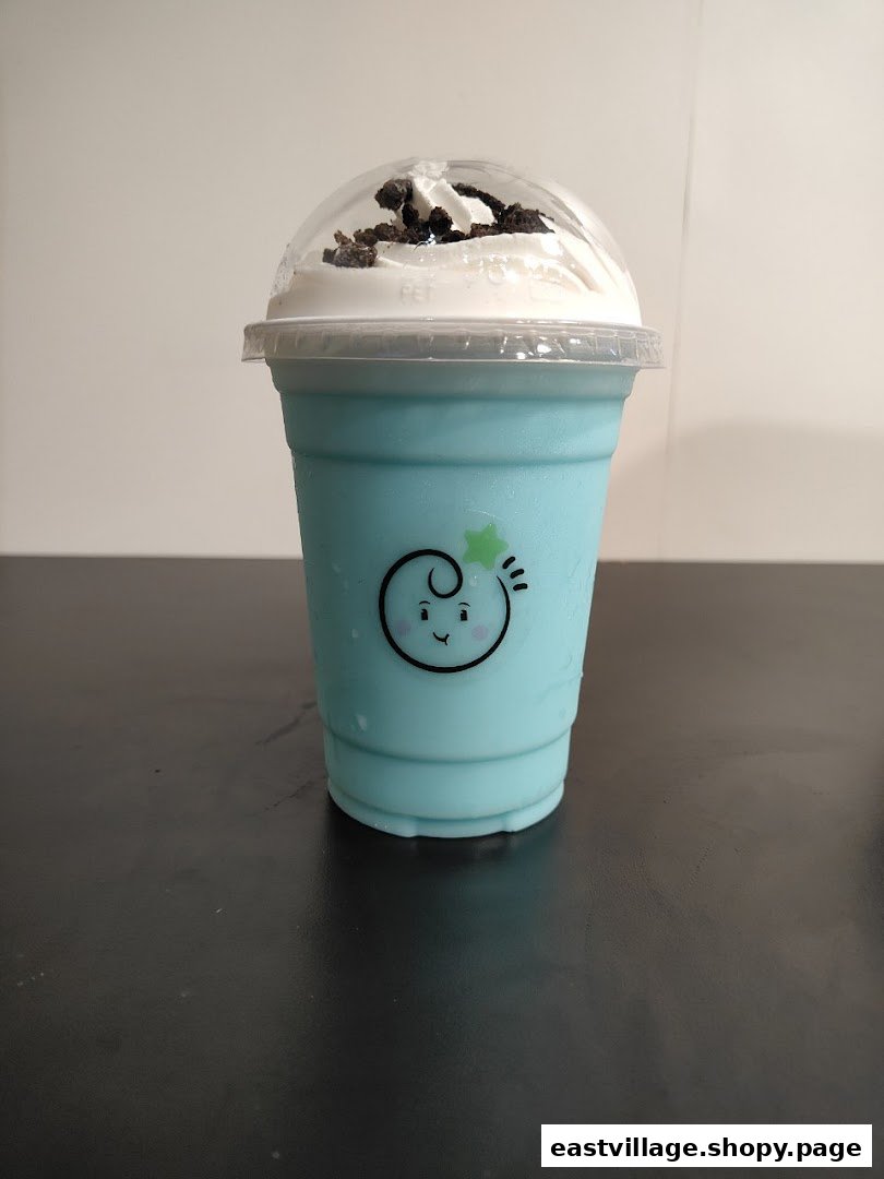 A vibrant blue drink topped with whipped cream and cookie crumbs in a clear cup.