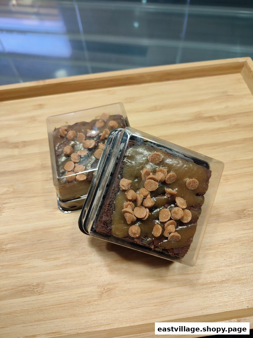 Two delicious caramel brownies with chocolate chips, individually packaged on a wooden tray.