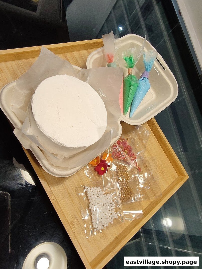 A DIY cake decorating kit featuring a plain cake, frosting bags, and colorful sprinkles on a wooden tray.