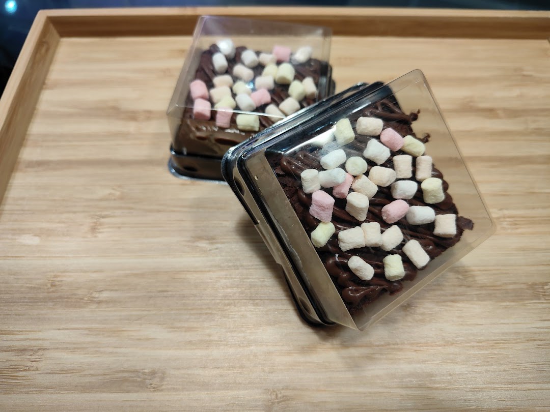 Two delicious chocolate desserts topped with colorful marshmallows in clear packaging on a wooden tray.