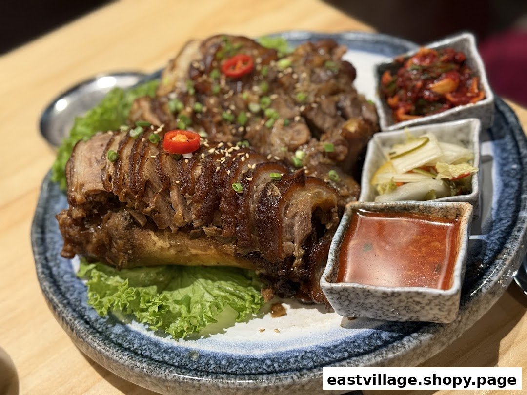 A plate of sliced Korean braised pig's trotters (Jokbal) with side dishes and dipping sauce.