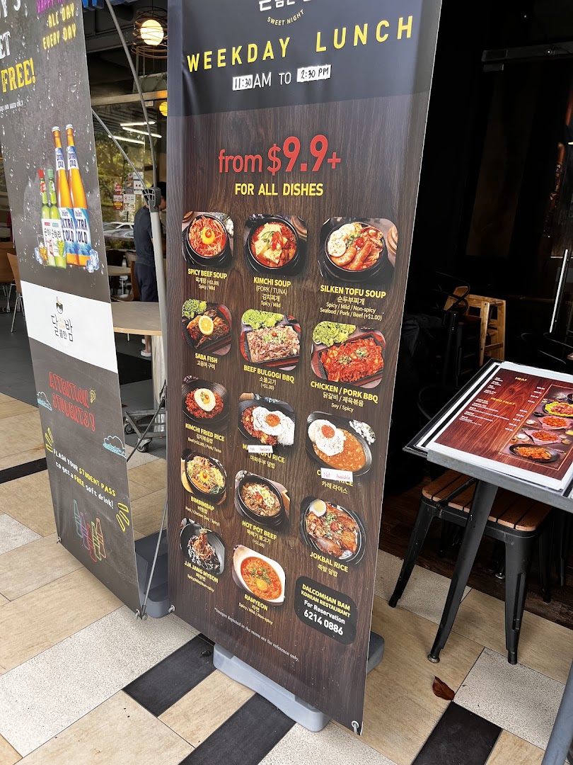 A standee displaying the weekday lunch menu and special offers for Dalcomhan Bam Korean Restaurant.