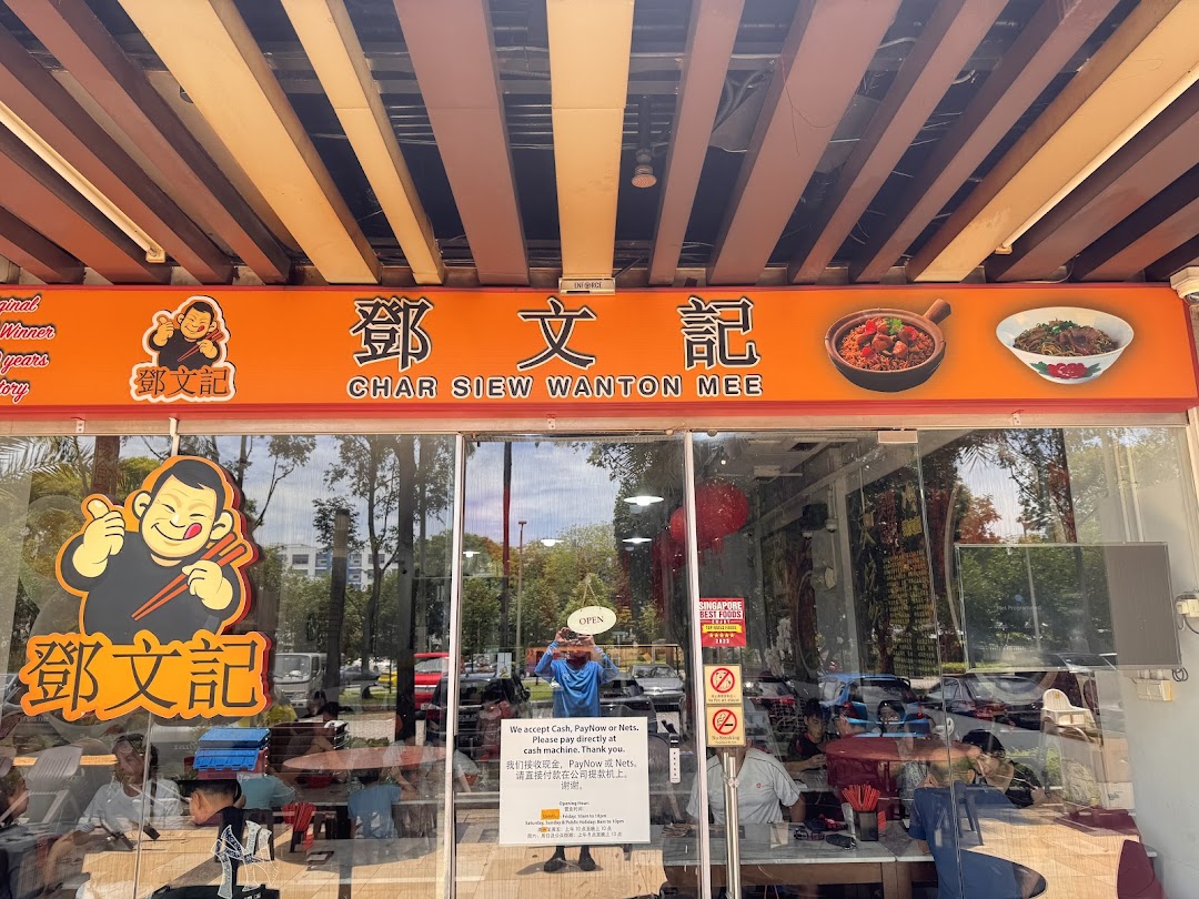 The vibrant orange storefront of Deng Wen Ji, a Char Siew Wanton Mee shop, with its logo and a glimpse of the interior.