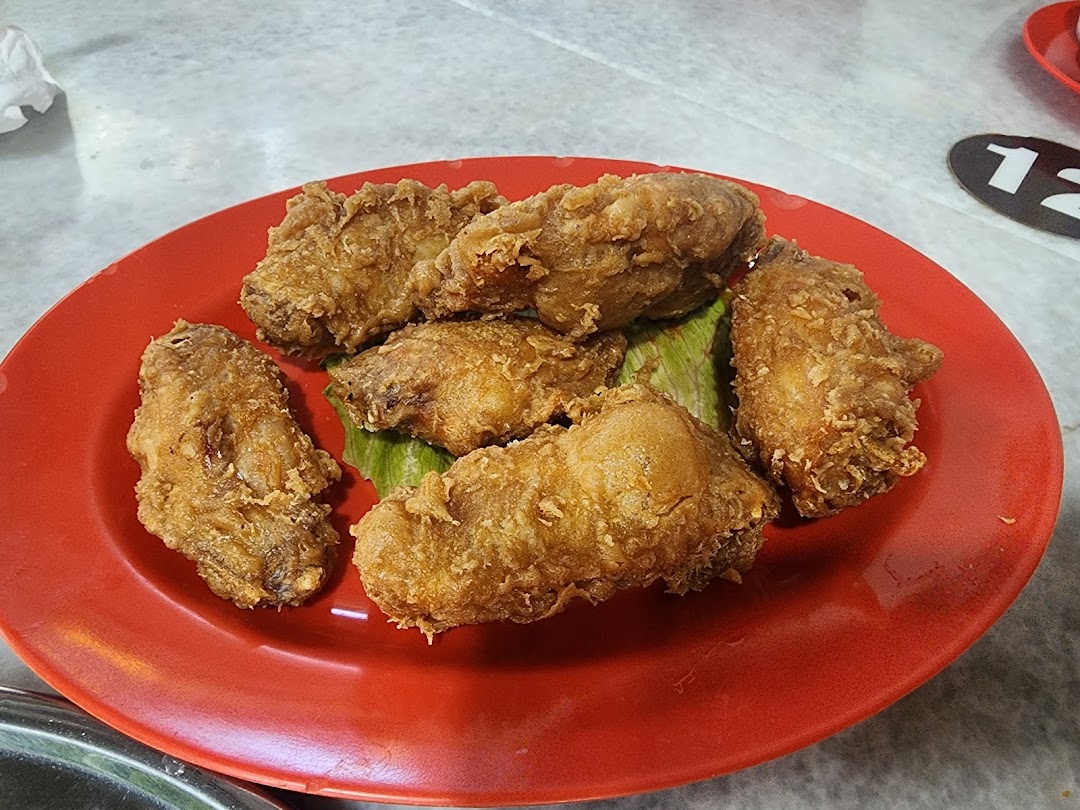 A red plate filled with crispy, golden-brown fried chicken pieces, garnished with green leaves.
