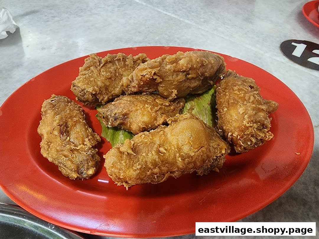 A red plate filled with crispy, golden-brown fried chicken pieces, garnished with green leaves.