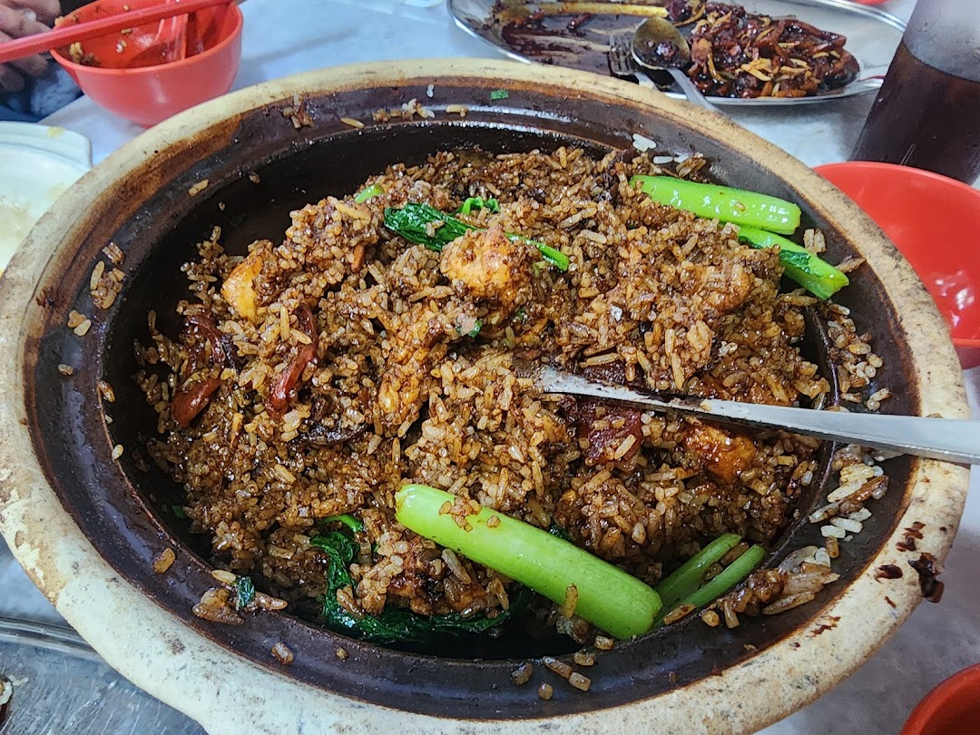 A close-up of delicious claypot rice with vegetables and meat, served in a traditional claypot.