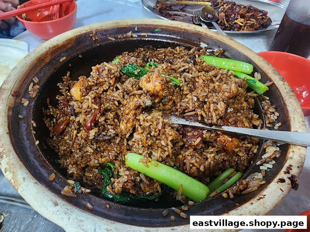A close-up of delicious claypot rice with vegetables and meat, served in a traditional claypot.