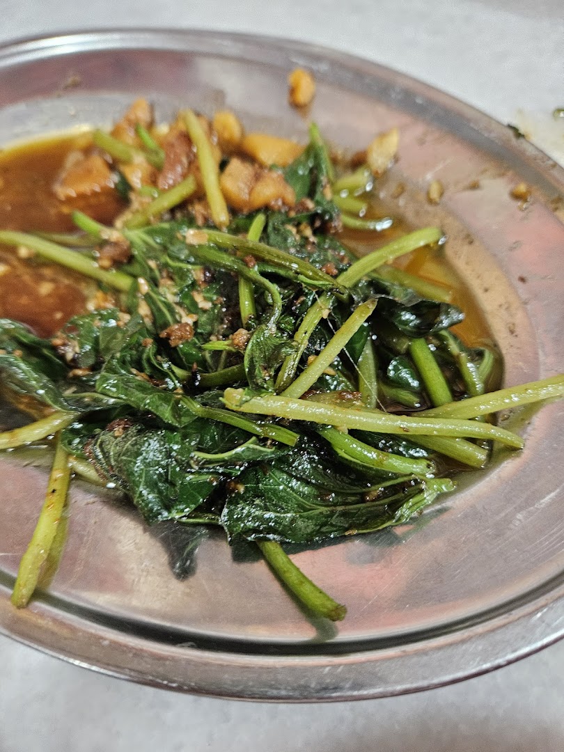 A close-up of a savory stir-fried green vegetable dish with sauce and other ingredients on a metal plate.