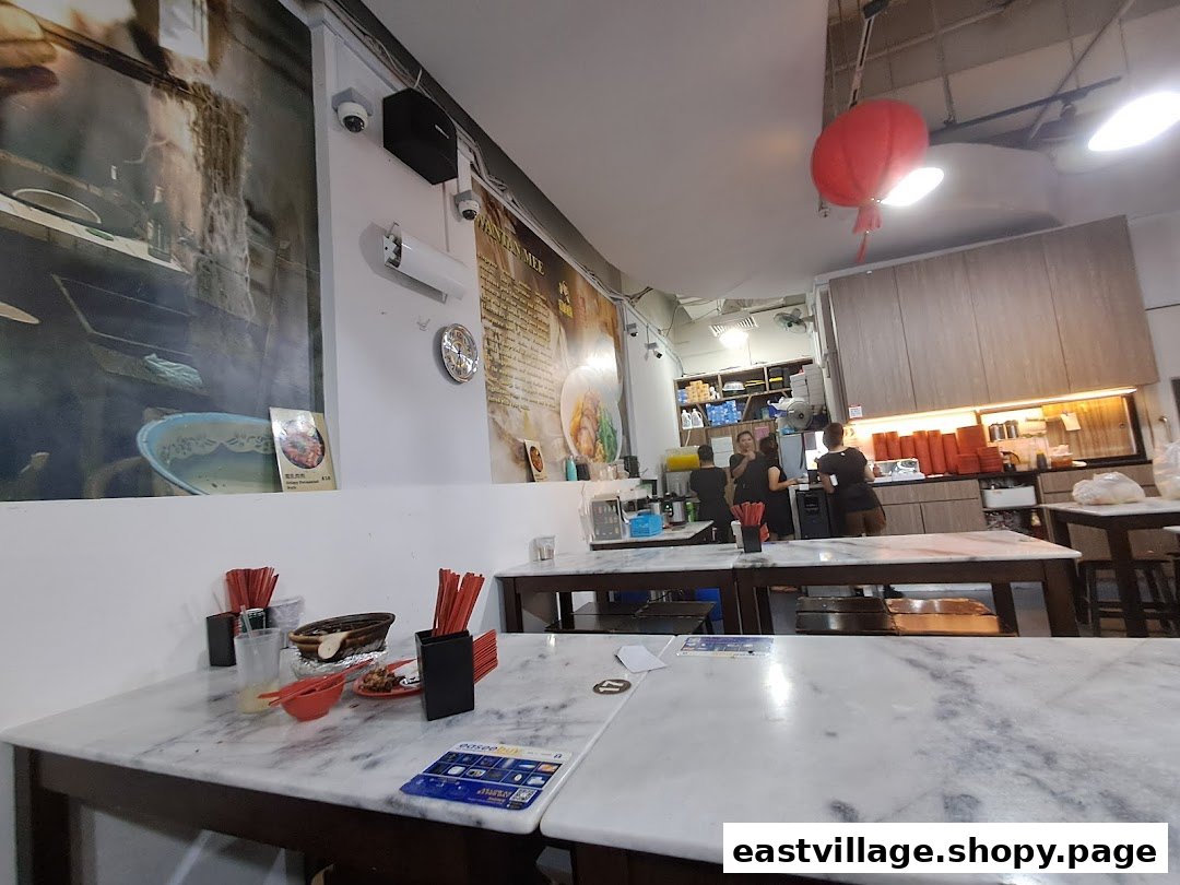 An interior view of Deng Wen Ji -East Village, featuring marble-top tables, a service counter, and wall murals.