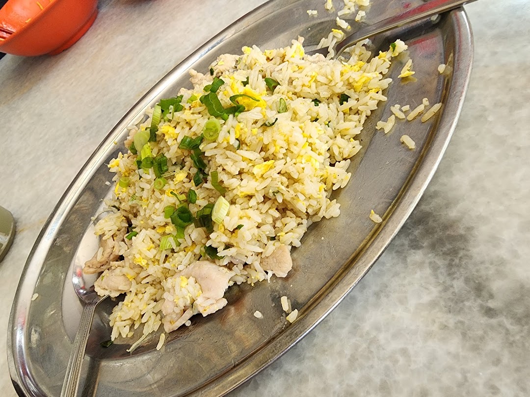A close-up of delicious fried rice with chicken and green onions served on a metal plate.