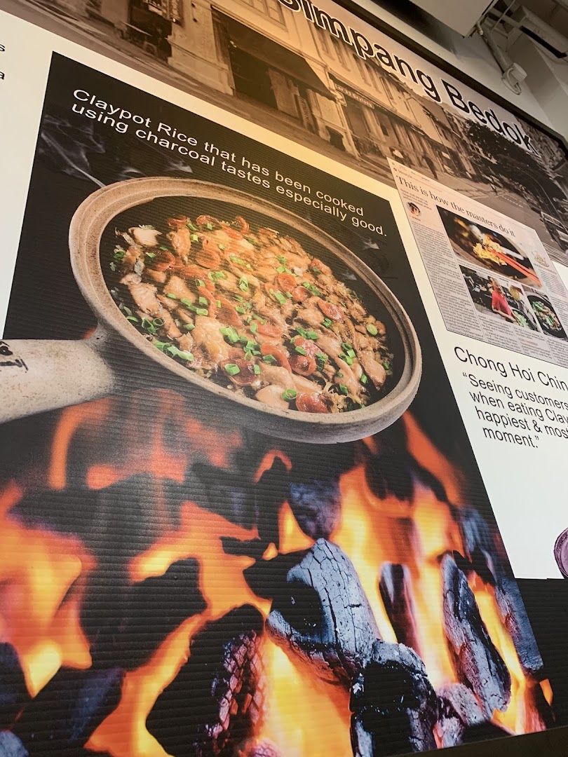 A large promotional poster showcasing claypot rice cooked over charcoal, with descriptive text.